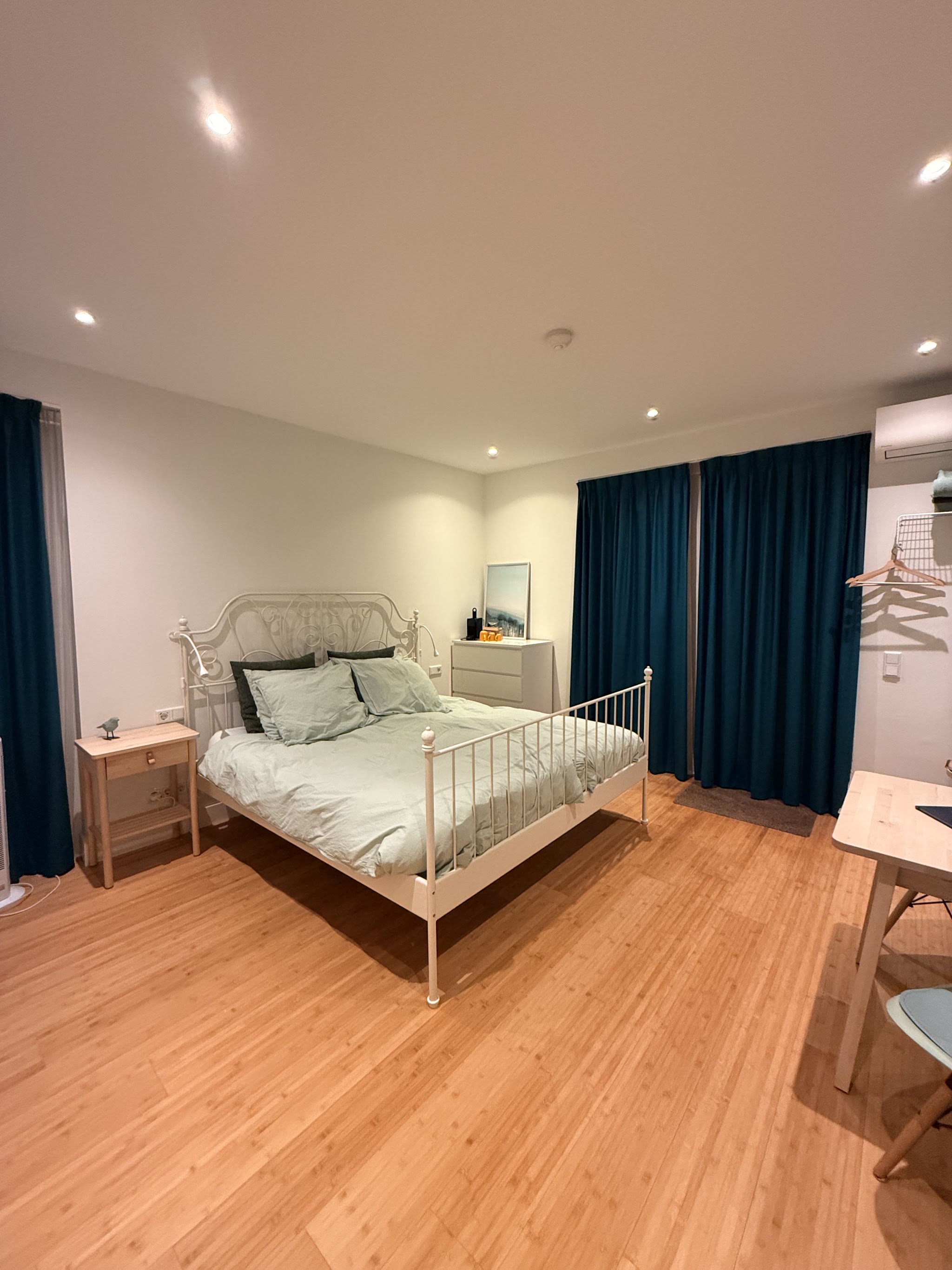 Opgeleverde slaapkamer met witte wanden, houten vloer en groene gordijnen