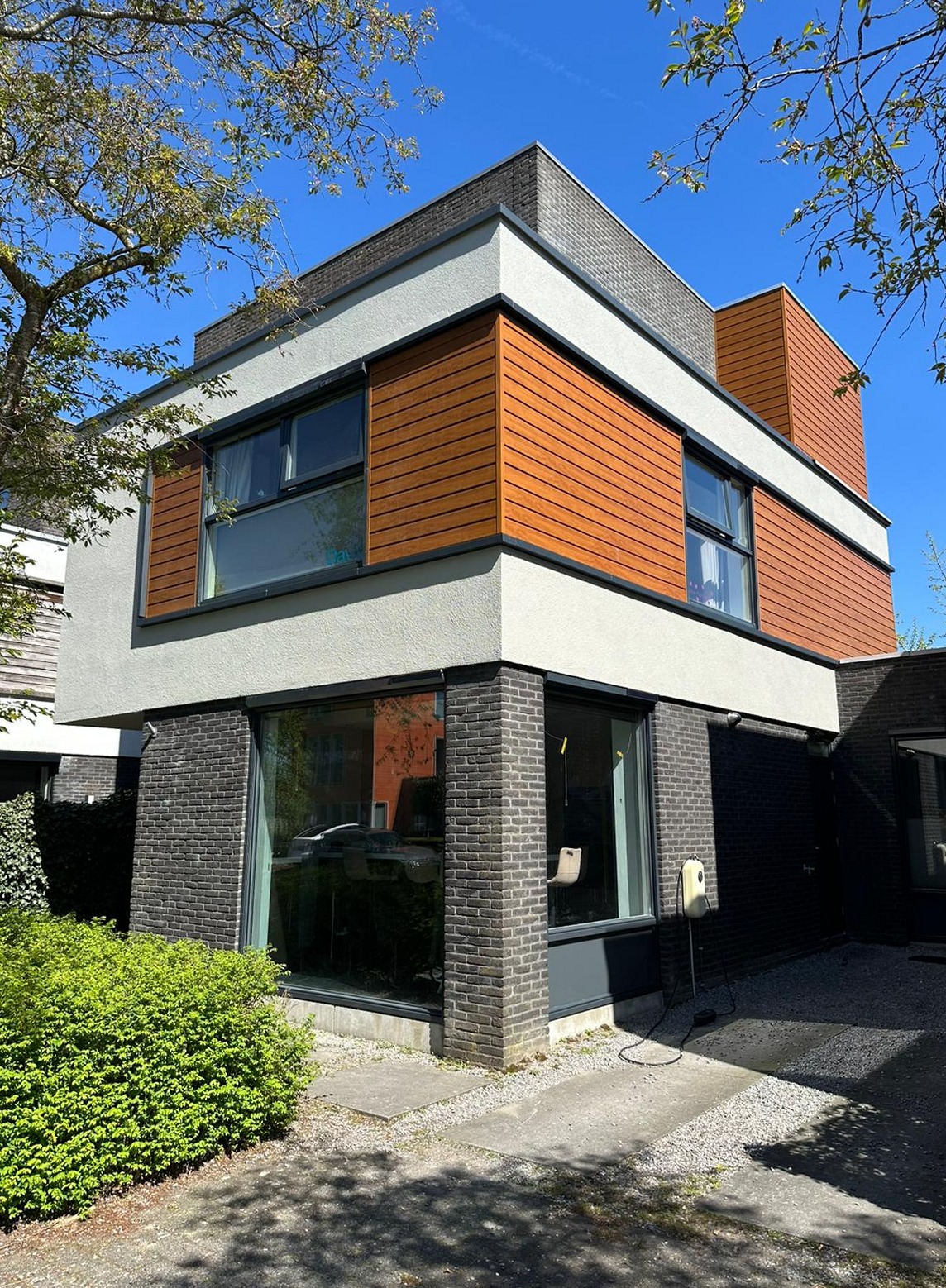 Woning in Oosterwold met geschilderd stucwerk en houten gevelbekleding, onder een blauwe lucht